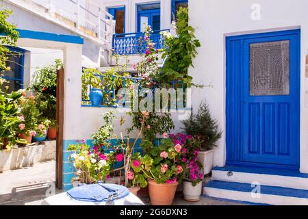 Plaka Town auf der Insel Milos - malerische schmale Steinstraße mit traditionellen griechischen weiß getünchten Wänden, blauen Türen, Fensterläden und blühenden Blumen. Stockfoto