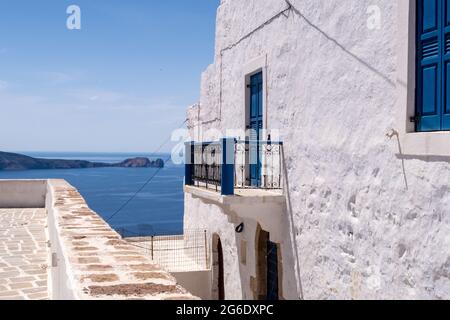 Meerblick von Plaka Town auf der Insel Milos, Griechenland, mit weiß getünchten traditionellen Haus mit blauen Fensterläden im Vordergrund und kristallklarem Himmel. Stockfoto