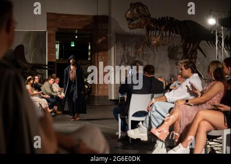 05. Juli 2021, Hessen, Frankfurt/M.: Während der Modenschau des Designers Samuel Gärtner im Senckenberg Museum läuft ein Modell vor dem Skelett eines Tyrannosaurus. Die Modenschau findet zu Beginn der Frankfurter Fashion Week statt, die vom 5. Bis 9. Juli stattfindet. Es ist jedoch nicht Teil des offiziellen Programms. Foto: Sebastian Gollnow/dpa Stockfoto