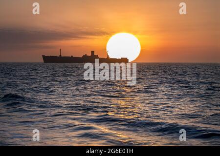 Wunderschöne Sonnenaufgangslandschaft über schwarzem Meer. Sonnenaufgang über dem Schiffswrack Stockfoto
