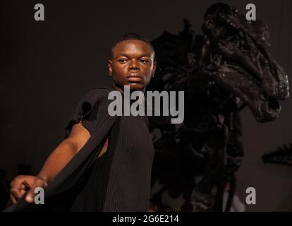 05. Juli 2021, Hessen, Frankfurt/M.: Während der Modenschau des Designers Samuel Gärtner im Senckenberg Museum läuft ein Modell vor dem Skelett eines iguanodons. Die Modenschau findet zu Beginn der Frankfurter Fashion Week statt, die vom 5. Bis 9. Juli stattfindet. Es ist jedoch nicht Teil des offiziellen Programms. Foto: Sebastian Gollnow/dpa Stockfoto