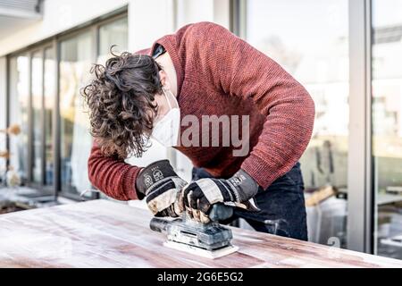 Junger Mann macht DIY, Schleiftisch mit einem Schleifer Stockfoto