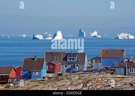 Holzhäuser vor riesigen Eisbergen, Qeqertarsuaq, Disko Island, Disko Bay, Grönland, Dänemark Stockfoto