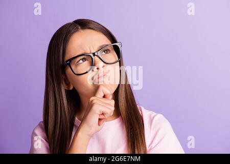 Foto von optimistisch schöne Brünette Mädchen Hand Kinn suchen leeren Raum tragen T-Shirt isoliert auf pastelllila Farbe Hintergrund Stockfoto