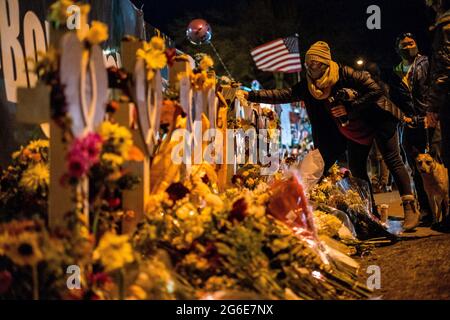 Boulder, Colorado, USA. März 2021. Eine Frau fügt Blumen zu einem Denkmal hinzu, das auf einem Zaun um den König Soopers errichtet wurde, wo bei einer Massenschießerei zehn Menschen in Boulder, Colorado, das Leben nahmen. Credit: ¬ Credit: Carl Payne/ZUMA Wire/ZUMAPRESS.com/Alamy Live News Stockfoto