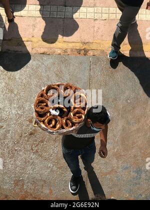 SIMIT-Verkäufer, der Simit in der Nähe von Fährbooten verkauft, die auf der Bosporus-See in Istanbul, Türkei, einsteigen Stockfoto