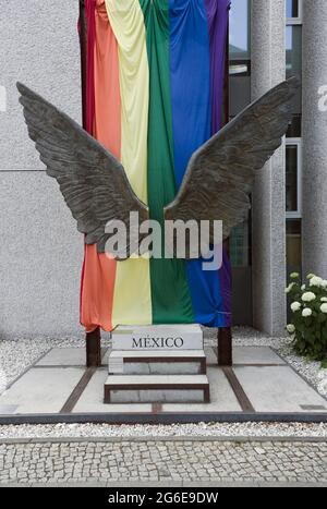 Ein Paar Flügel als Skulptur, dahinter die Regenbogenfahne an der Außenwand der mexikanischen Botschaft, Berlin, Deutschland Stockfoto