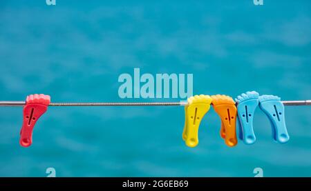 Wäscheklammern auf leeren Wäscheleine, verwischen blauen Hintergrund. Bunte Plastikstifte hängen an der Edelstahlschiene des Bootes. Sommerferien und Segeln, Clo Stockfoto