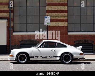 London, Greater London, England - 12 2021. Juni: Der weiße und schwarze Porsche Carrera parkte auf einer Straße mit einem Parkschild dahinter. Stockfoto