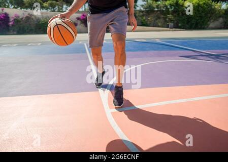 Beine eines professionellen Basketballspielers, der den Ball auf dem Basketballfeld Dribbeln kann. Das Spiel ist in vollem Gange Stockfoto