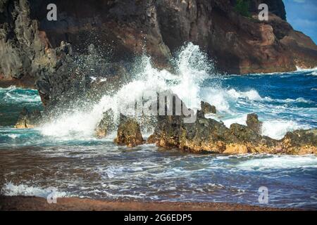 Die Welle trifft am Strand auf den Felsen, das Meerwasser spritzt auf das Meer. Seascape. Spritzer von den Wellen, die gegen das felsige Ufer stoßen. Stockfoto