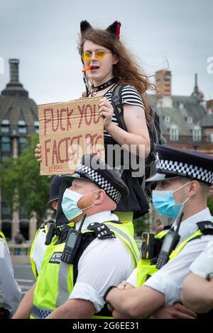 Ein junger Protestler, der Katzenohren und gelbe Brille trägt, hält ein Schild unter der Polizei beim Protest „Kill the Bill“ im Zentrum von London, 5.7.2021, hoch Stockfoto