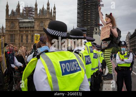 Ein junger Protestler, der Katzenohren und gelbe Brille trägt, hält ein Schild unter der Polizei beim Protest „Kill the Bill“ im Zentrum von London, 5.7.2021, hoch Stockfoto