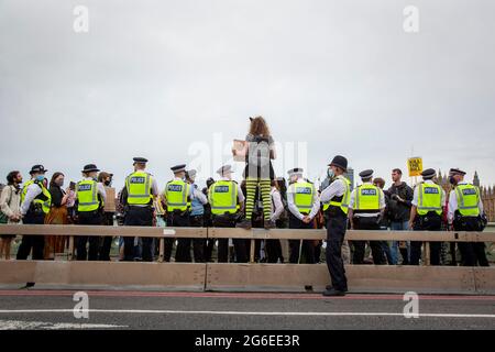 Ein junger Protestler, der Katzenohren und gelbe Brille trägt, hält ein Schild unter der Polizei beim Protest „Kill the Bill“ im Zentrum von London, 5.7.2021, hoch Stockfoto