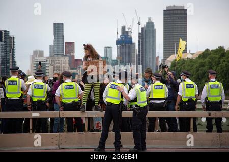 Ein junger Protestler, der Katzenohren und gelbe Brille trägt, hält ein Schild unter der Polizei beim Protest „Kill the Bill“ im Zentrum von London, 5.7.2021, hoch Stockfoto