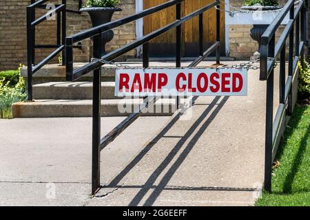 Rot-weißes Schild mit der Aufschrift „Rampe geschlossen“. An schwarze eiserne Handläufe gekettet. Vor dem Eingang der Kirche. Stockfoto