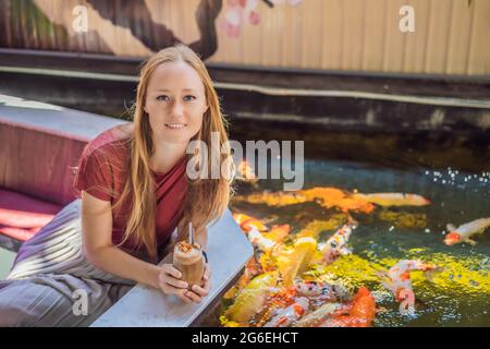 Frau füttert Koi-Fische. Schöne Koi Fische schwimmen im Teich Stockfoto