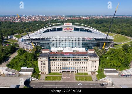 14. Juni 2021, Sachsen, Leipzig: Fußball: Bundesliga, RB Leipzig. Zwei Krane stehen in der Red Bull Arena. Das Heimgelände der Rasenballer wird umgebaut. Die Zuschauerkapazität wird von 42,558 auf 47,069 im Steh- und Sitzbereich erhöht. Die Außenseite des Stadions ist von einer schalldichten Fassade umgeben. Der Damm des ehemaligen Zentralstadions, das die Arena umfasst, wurde hinter dem historischen Glockenturm aufgeschnitten, um Platz für einen neuen Eingang zu schaffen. RB Leipzig investiert bis 2022 gut 60 Millionen Euro in den Umbau. (Luftaufnahme mit Drohne) Foto: Jan Woitas/dpa-Zentralbild/dpa Stockfoto