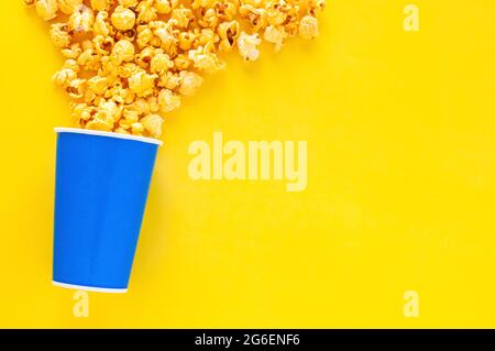 Süßer Karamell Popcorn in blauem Papiereimer auf gelbem Hintergrund. Stockfoto