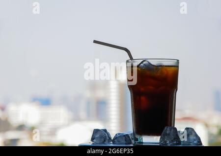 Ein Glas schwarzen Eiskaffees auf dem Tisch mit Eiswürfel. Sommerdrink-Konzept. Stockfoto
