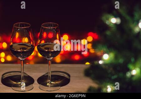 Zwei Gläser Rose Wein auf Holztisch mit Weihnachtsbaum und bunten Bokeh hellen Hintergrund. Stockfoto