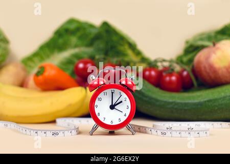 Konzept zum Abnehmen, indem Sie zu bestimmten Zeiten nur gesunde Lebensmittel mit Gemüse, Obst, Maßband und Uhr essen Stockfoto