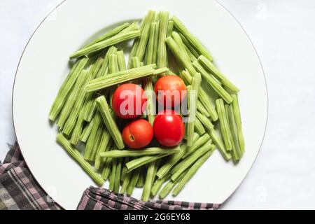 Tomaten mit Drumstick-Stücken auf weißem Teller, Draufsicht, leckeres Essen Stockfoto
