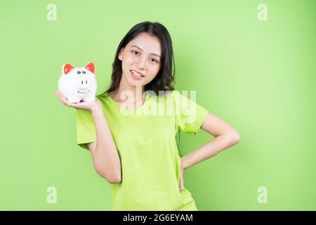 asiatische Mädchen halten Sparschwein in ihrer Hand Geld sparen Konzept Stockfoto