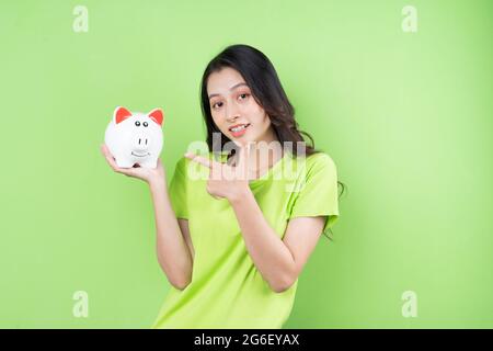 asiatische Mädchen halten Sparschwein in ihrer Hand Geld sparen Konzept Stockfoto