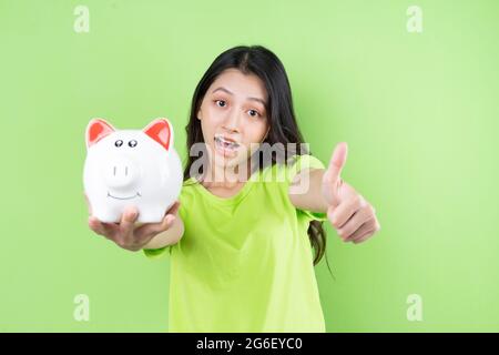 asiatische Mädchen halten Sparschwein in ihrer Hand Geld sparen Konzept Stockfoto