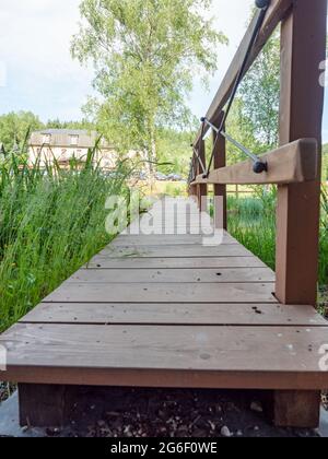 Romantischer Garten mit Holzbrücke. Morgenspaziergang im Garten Stockfoto