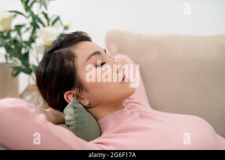 Glückliche Frau liegt bequem auf einer Couch am Morgen zu Hause Stockfoto