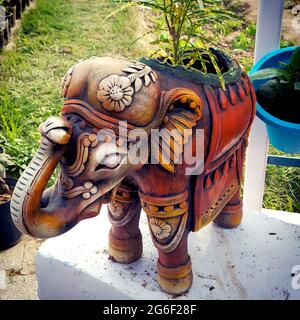 Nahaufnahme eines schönen Tonblumentöpfes in Form eines Elefanten mit kleinen grünen Blättern und Reben, die im Inneren auf einem grünen Asphalt wachsen Stockfoto