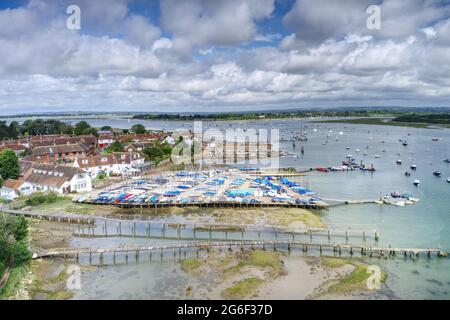 Itschenor in West Sussex mit kleinen Booten neben der Anlegestelle mit Yachten und Booten an der Mündung plus Blick auf die Werft. Luftaufnahme. Stockfoto