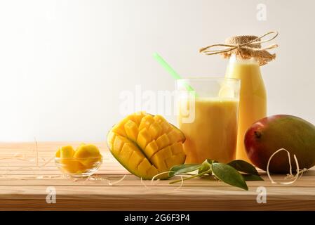 Bio-Anbau Mangosaft in Glas und Flasche zusammen mit Obst auf Holztisch und weiß isoliert Hintergrund. Vorderansicht. Stockfoto