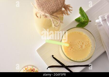 Milchgetränk mit Vanille in Glasbehältern auf Küchenbank und Vanillestock. Draufsicht. Stockfoto