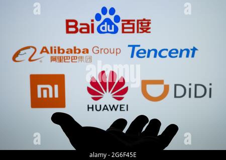 Silhouette aus dunkler Hand und verschwommenen chinesischen Big-Tech-Firmen-Logos Baidu Alibaba Tencent Xiaomi Huawei Didi. Konzept. Echtes Foto, keine Montage. Sta Stockfoto