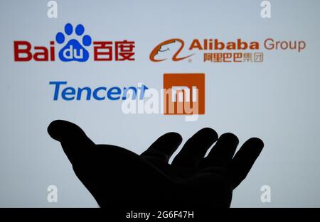 Silhouette aus dunkler Hand und verschwommenen chinesischen Big Tech-Logos, bekannt als BATX Baidu Alibaba Tencent Xiaomi. Konzept. Echtes Foto, keine Montage. Stafford, U Stockfoto