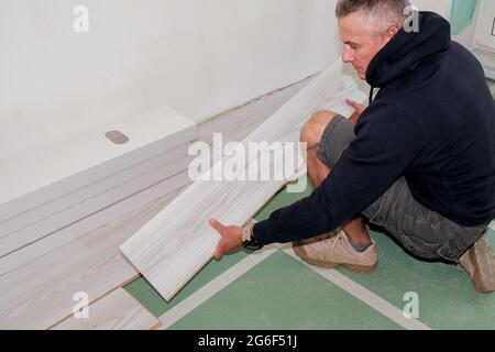 Ein Arbeiter, der den Laminatboden während der Renovierung des Hauses verbindet. Stockfoto