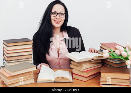 Schöne Geschäftsfrau in Business-Anzug an einem Tisch mit Stapel von Lehrbüchern Stockfoto