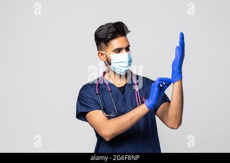 Der indische Arzt zieht Handschuhe an und trägt eine medizinische Maske. Medizinisches Konzept Corona Virus Stockfoto