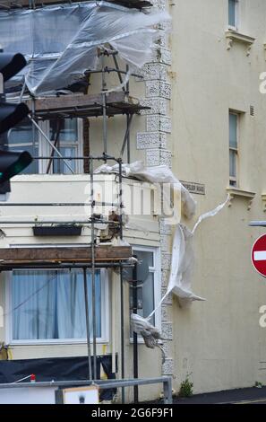 Brighton UK 6. Juli 2021 - Plastikfolien auf Gerüsten werden auseinandergerissen, während starke Winde heute Morgen die Südküste mit Böen von bis zu 40 Meilen pro Stunde für einige Gebiete vorhersagen : Credit Simon Dack / Alamy Live News Stockfoto