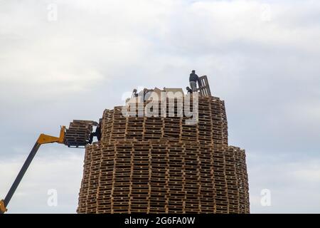 4. Juli 2021 Jugendliche auf dem sehr hohen Lagerfeuer aus tausenden von industriellen Holzpaletten, während sie sich auf die Feierlichkeiten zum 12. Juli vorbereiten Stockfoto