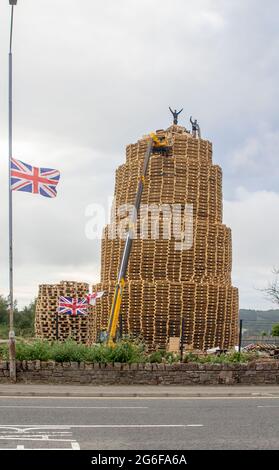 4. Juli 2021 Jugendliche auf dem sehr hohen Lagerfeuer aus tausenden von industriellen Holzpaletten, während sie sich auf die Feierlichkeiten zum 12. Juli vorbereiten Stockfoto
