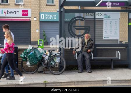 4. Juli 2021 EIN obdachloser älterer Herr mit seinem Fahrrad, das neben ihm steht, nimmt seinen gewohnten Platz für die Nacht in einem Translink Bus Shelter auf der Lo ein Stockfoto