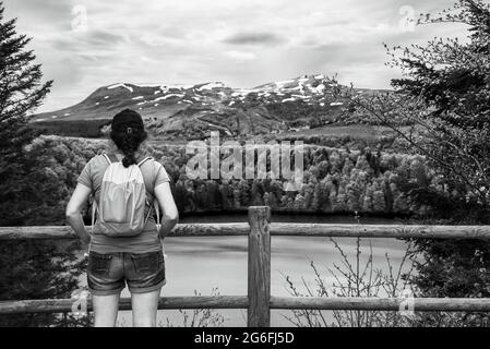 Junge Frau mit Quechua-Rucksack, die den Blick auf den See Pavin im regionalen Vulkannaturpark Auvergne, Frankreich, bewundert. Aktivurlaub in der Natur Stockfoto