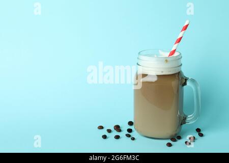 Glas mit Eiskaffee und Bohnen auf blauem Hintergrund Stockfoto