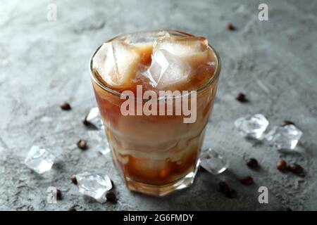 Glas Eiskaffee, Bohnen und Eis auf einem grauen Tisch mit Struktur Stockfoto