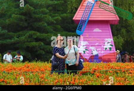 Shenyang, Chinas Provinz Liaoning. Juli 2021. Im Shenshuiwan Park in Shenyang, nordöstlich der chinesischen Provinz Liaoning, nehmen Menschen Selfies neben Lilien auf, 6. Juli 2021. Quelle: Yang Qing/Xinhua/Alamy Live News Stockfoto