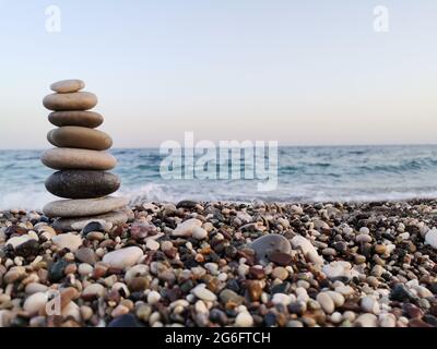 Die Kunst des Gleichgewichts aus Steinen am Strand. Mittelmeer im Hintergrund. Stockfoto